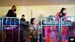 FILE - Single mothers and their children crowd into a room with bunk beds at a shelter in Tijuana, Mexico, Dec. 21, 2022.