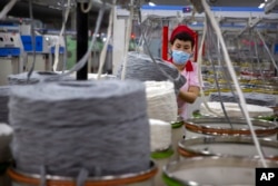 FILE - A worker gathers cotton yarn at a textile manufacturing plant, as seen during a government organized trip for foreign journalists, in Aksu in western China's Xinjiang Uyghur Autonomous Region, April 20, 2021.