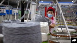 FILE - A worker gathers cotton yarn at a textile manufacturing plant, as seen during a government organized trip for foreign journalists, in Aksu in western China's Xinjiang Uyghur Autonomous Region, April 20, 2021. 