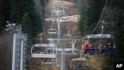 Des gens montent sur le télésiège au-dessus de la piste de ski sans aucune neige sur la montagne Bjelasnica près de Sarajevo, en Bosnie, le 4 janvier 2023.