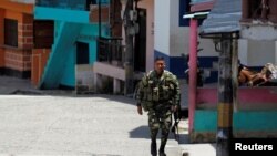 Un soldado camina por una calle en Valdivia después de que el gobierno colombiano ordenara la evacuación de los residentes que viven a lo largo del río Cauca, en Valdivia, Colombia, el 19 de mayo de 2018.