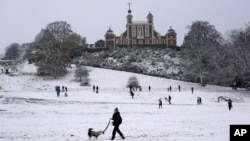 FILE - People walk at a snow-covered Greenwich Park in London, Dec. 12, 2022. Snow and ice swept across parts of the United Kingdom in a year that had seen record high temperatures.