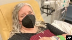 This photo provided by Amy Watson of Portland, Ore., shows her during an iron infusion in December 2022. Watson, approaching 50, says she has “never had any kind of recovery” from COVID-19.(Amy Watson via AP)