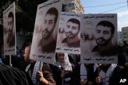 FILE - Aksi protes warga Palestina dengan memegang poster tahanan Palestina Nasser Abu Hamid di depan kantor Komite Internasional Palang Merah di Kota Gaza, Selasa, 20 Desember 2022. (AP/Adel Hana, File)