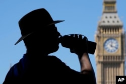 FILE - A tourist takes a drink opposite the Elizabeth Tower also known as Big Ben in London, Thursday, Aug. 11, 2022.