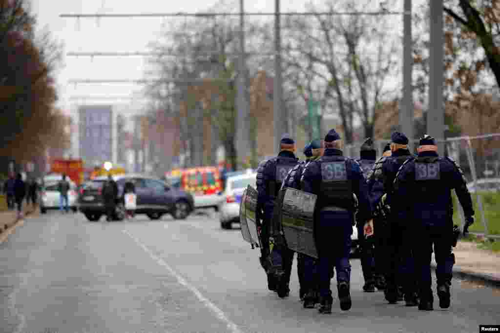 French riot police walk near the scene of a massive building fire where 10 people died, in Vaulx-en-Velin, near Lyon, France.