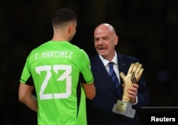 El presidente de la FIFA, Gianni Infantino, otorga el trofeo del guante de oro al argentino Emiliano "Dibu" Martínez.