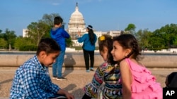 FILE - The Safi family celebrates Eid by taking family photographs on the National Mall, May 3, 2022, near the US Capitol in Washington. The family was evacuated from Afghanistan and is trying to make a new life in the US.