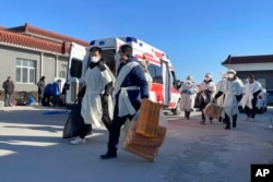 Relatives carry paper offerings to burn for their dead relative at the Gaobeidian Funeral Home in northern China's Hebei province, Thursday, Dec. 22, 2022. Bodies from Beijing, a two-hour drive away, are appearing at the Gaobeidian funeral home, because similar funeral homes in Beijing were packed. (AP Photo)