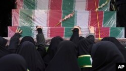 Para pelayat menyentuh peti mati terbungkus bendera tentara Iran tak dikenal yang terbunuh saat perang Iran-Irak tahun 1980-1988, dalam prosesi pemakaman mereka di Teheran, Iran, Selasa, 27 Desember 2022. (Foto AP/Vahid Salemi)