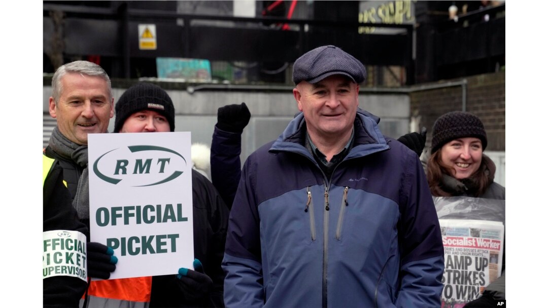 Mick Lynch, Sekjen Serikat Pekerja Kereta Api, Maritim dan Transportasi (RMT), (depan), bergabung dengan para pekerja kereta api dalam aksi mogok di luar stasiun Euston di London, Selasa, 13 Desember 2022. (AP/Kin Cheung)