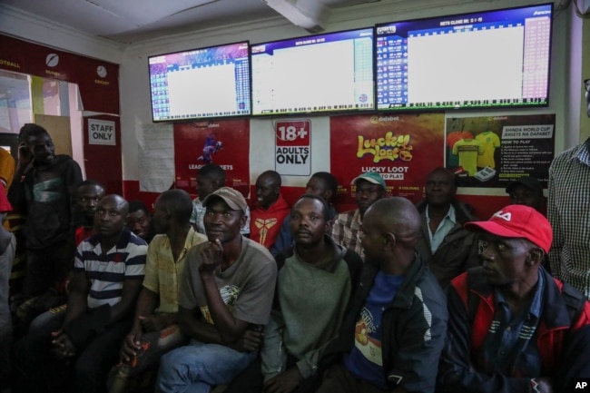 Customers watch screens in a sports betting shop in the low-income Kibera neighborhood of the capital Nairobi, Kenya, Monday, Dec. 5, 2022. (AP Photo/Brian Inganga)