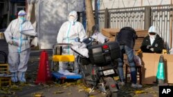 Workers in protective clothing control access into a community under lockdown in Beijing, Nov. 25, 2022.