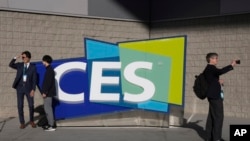 FILE - People take pictures in front of a sign during the CES tech show on Jan. 6, 2022, in Las Vegas.