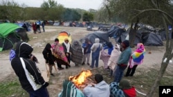 ARCHIVO - Migrantes soportan un tiempo frío alrededor de una fogata en un campamento improvisado en la frontera entre Estados Unidos y México, el 23 de diciembre de 2022 en Matamoros, México. 