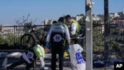 Members of Zaka Rescue and Recovery team clean blood from the scene of an explosion at a bus stop in Jerusalem, Nov. 23, 2022. 