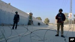 Security officials guard a blocked road leading to a counterterrorism center after security forces started to clear the compound seized earlier by Pakistani Taliban militants in Bannu, Pakistan, Dec. 20, 2022.