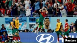 Cristiano Ronaldo celebrates scoring a goal against Ghana with a banner of Lionel Messi behind him at the 2022 FIFA World Cup