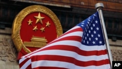 美国国旗，背景为中国国徽。（美联社照片）