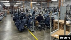 FILE: People work at Saitex's factory, which experiments with new robots to cut the cost of making blue jeans, in Los Angeles, California. Taken Sept. 21, 2022. 