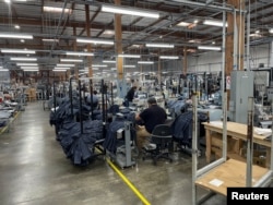 FILE - People work at Saitex's factory, which experiments with new robots to cut the cost of making blue jeans, in Los Angeles, California, U.S. September 21, 2022. (REUTERS/Timothy Aeppel)