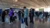 Pelancong bermasker menggunakan smartphone mereka untuk mengisi pernyataan kesehatan mereka setelah check-in di konter check-in penerbangan internasional di Bandara Internasional Beijing, China, Kamis, 29 Desember 2022. (AP/Andy Wong)