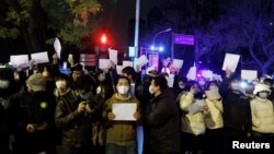 Para demonstran yang marah dengan kebijakan ketat COVID-19, meneriakkan slogan-slogan dalam protes di Beijing. Mereka menyerukan agar pemimpin kuat China Xi Jinping mengundurkan diri, sebuah aksi protes yang jarang terjadi kepada Partai Komunis yang berkuasa. (Foto: AP) 