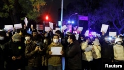 2022年11月28日，在中国北京，随着新冠肺炎疫情的持续，人们在为乌鲁木齐火灾遇难者守夜后，手持白纸抗议新冠肺炎疫情限制措施。