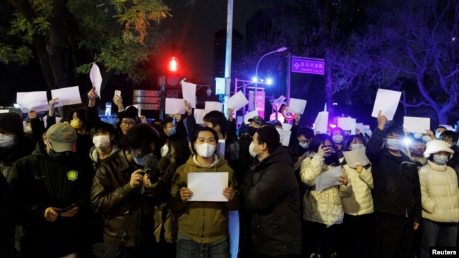 2022年11月28日,在中国北京,随着新冠肺炎疫情的持续,人们在为乌鲁木齐火灾遇难者守夜后,手持白纸抗议新冠肺炎疫情限制措施。