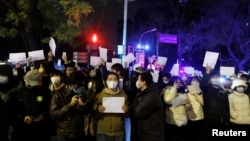 2022年11月28日，在中国北京，随着新冠肺炎疫情的持续，人们在为乌鲁木齐火灾遇难者守夜后，手持白纸抗议新冠肺炎疫情限制措施。