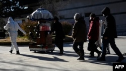 Family members follow an urn containing the ashes of a loved one at a crematorium in Beijing on Dec. 22, 2022.