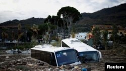 Dua bus yang rusak tampak di antara puing-puing setelah tanah longsor melanda pulau Ischia, salah satu destinasi liburan di Italia, Minggu 27 November 2022.