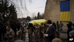 Ukrainian soldiers carry the coffin of Dmytro Kyrychenko near Kyiv, Ukraine, Dec. 23, 2022. Upon returning to Kyiv after visiting the U.S., Ukraine President Volodymyr Zelenskyy said Ukrainian forces “are working toward victory” despite Russia’s relentless attacks on the country.
