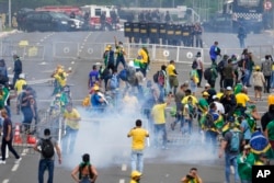 Para pengunjuk rasa, pendukung mantan Presiden Jair Bolsonaro, bentrok dengan polisi saat berunjuk rasa di luar gedung Istana Planalto di Brasilia, Brazil, 8 Januari 2023. (Foto: A/Eraldo Peres)