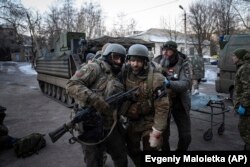 A Ukrainian serviceman carries his injured comrade evacuated from the battlefield into a hospital in the Donetsk region on January 9, 2023. (Evgeniy Maloletka/AP)