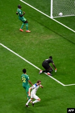 England's forward Harry Kane kicks the ball and scores his team's second goal past Senegal's goalkeeper Edouard Mendy during the Qatar 2022 World Cup round of 16 match December 4, 2022.