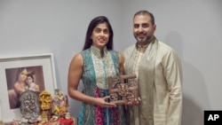 Sheetal Deo and her husband, Sanmeet Deo, hold a Hindu swastika symbol in their home in Syosset, N.Y., Nov. 13, 2022. Hindus, Buddhists and Native Americans are trying to rehabilitate the swastika, to restore it to a place of sanctity in their faiths.