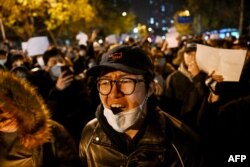 Para pengunjuk rasa berbaris di sepanjang jalan di China di Beijing pada 28 November 2022. (Foto: AFP)