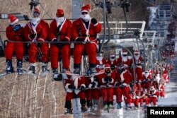 Para pemain ski berpakaian Sinterklas menaiki lift untuk berpartisipasi dalam acara amal Santa Sunday di resor ski Sunday River di Bethel, Maine, AS, 5 Desember 2021. (Foto: REUTERS/Brian Snyder)