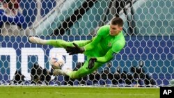 El portero de Croacia, Dominik Livakovic, hace una atajada durante la tanda de penales en el partido de fútbol de octavos de final de la Copa Mundial ante Japón en el estadio Al Janoub en Al Wakrah, Qatar, el lunes 5 de diciembre de 2022. 