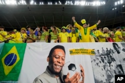 FILE - Brazil fans cheer by a banner celebrating Pele before the World Cup match between Brazil and South Korea, at Al Rayyan, Qatar, Dec. 5, 2022.