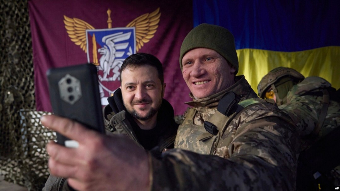 FILE - In this photo provided by the Ukrainian Presidential Press Office, a Ukrainian soldier takes a selfie with President Volodymyr Zelenskyy, left, in Sloviansk, Donbas region, Ukraine, Dec. 6, 2022. In a recent speech, Zelenskyy praised front-line workers.