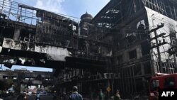 People next to a destroyed part of the Grand Diamond City hotel-casino after a fire in Poipet on December 29, 2022. (Photo by Lillian SUWANRUMPHA / AFP)