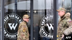 Des visiteurs portant un camouflage militaire se tiennent à l'entrée du 'PMC Wagner Center', associé au fondateur du groupe militaire privé Wagner (PMC) Yevgeny Prigozhin, lors de l'ouverture officielle de l'immeuble de bureaux le jour de l'unité nationale, à Saint-Pétersbourg.