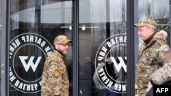 Des visiteurs portant un camouflage militaire se tiennent à l'entrée du 'PMC Wagner Center', associé au fondateur du groupe militaire privé Wagner (PMC) Yevgeny Prigozhin