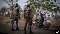 FILE: A police officer and a soldier from Benin stop a motorcyclist at a checkpoint outside Porga, Benin, March 26, 2022. Porga, in the Atakora region of northern Benin bordering Burkina Faso, has suffered violence linked to al-Qaida and the Islamic State group in the Sahel. 