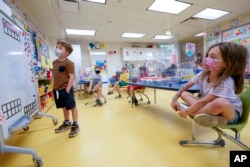 FILE - Kindergarten students wear face masks and are seated at proper social distancing spacing during a math lesson at the Milton Elementary School, Tuesday, May 18, 2021. (AP Photo/Mary Altaffer)