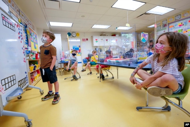 FILE - Kindergarten students wear face masks and are seated at proper social distancing spacing during a math lesson at the Milton Elementary School, Tuesday, May 18, 2021. (AP Photo/Mary Altaffer)