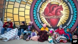 Migrants try to stay warm outside the Sacred Heart Church in El Paso, Texas, Dec. 18, 2022. Doctors, social workers, clergy and shelter directors say migrants are arriving at the U.S.-Mexican border in desperate need of trauma-informed medical and mental health treatment.