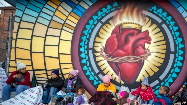 Migrants try to stay warm outside the Sacred Heart Church in El Paso, Texas, Dec. 18, 2022.